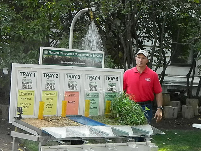 After a congressional hearing Thursday on soil health, staff from the Natural Resources Conservation District held a rainfall demonstration outside of USDA&#039;s main headquarters building in Washington. Chris Lawrence, an NRCS agronomist from Virginia, looks on as the simulator shows runoff from various types of tillage and grazing practices. (DTN photo by Chris Clayton)
