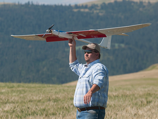 The first UAVs -- legally -- to commercially scout agricultural fields are owned by an Idaho company, Empire Unmanned. Here partner and farmer Robert Blair launches a fixed winged aircraft to fly over a wheat field. (DTN/The Progressive Farmer photo by Geoff Crimmins)